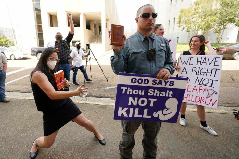 Anti-abortion activist Gabriel Olivier, center, holds his Bible and a message sign while...