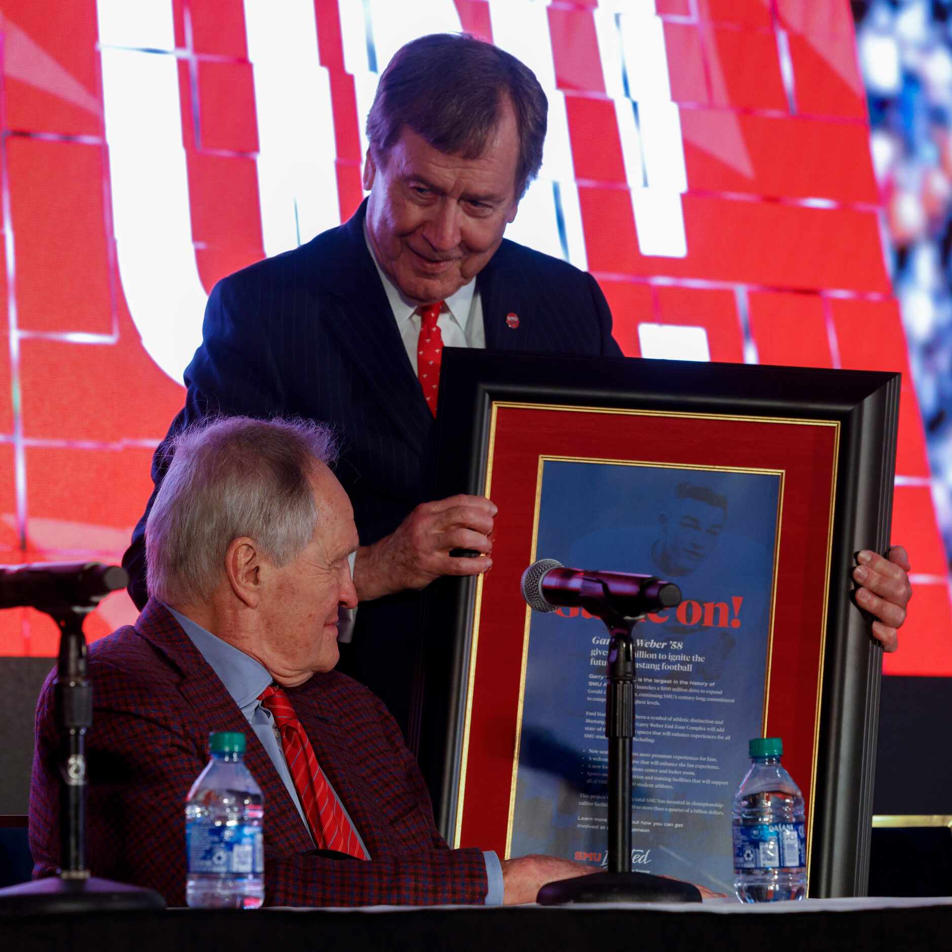 SMU President R. Gerald Turner presents SMU alumnus Garry Weber with a framed copy of a full...