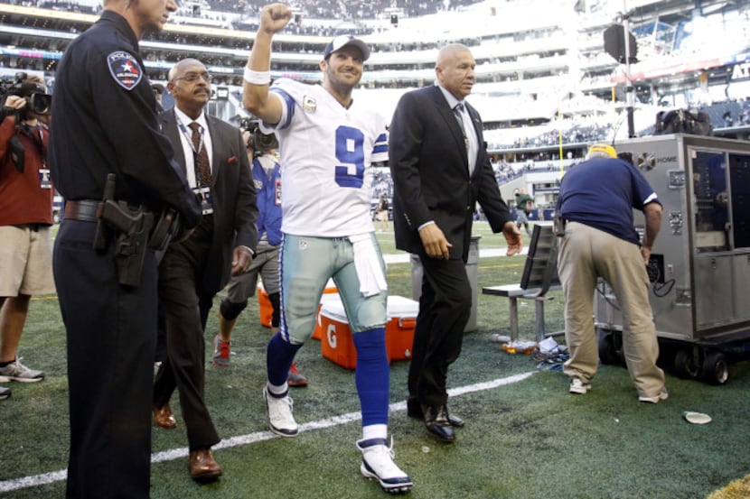 Dallas Cowboys quarterback Tony Romo (9) smiles and pumps his fist as he exits the field in...