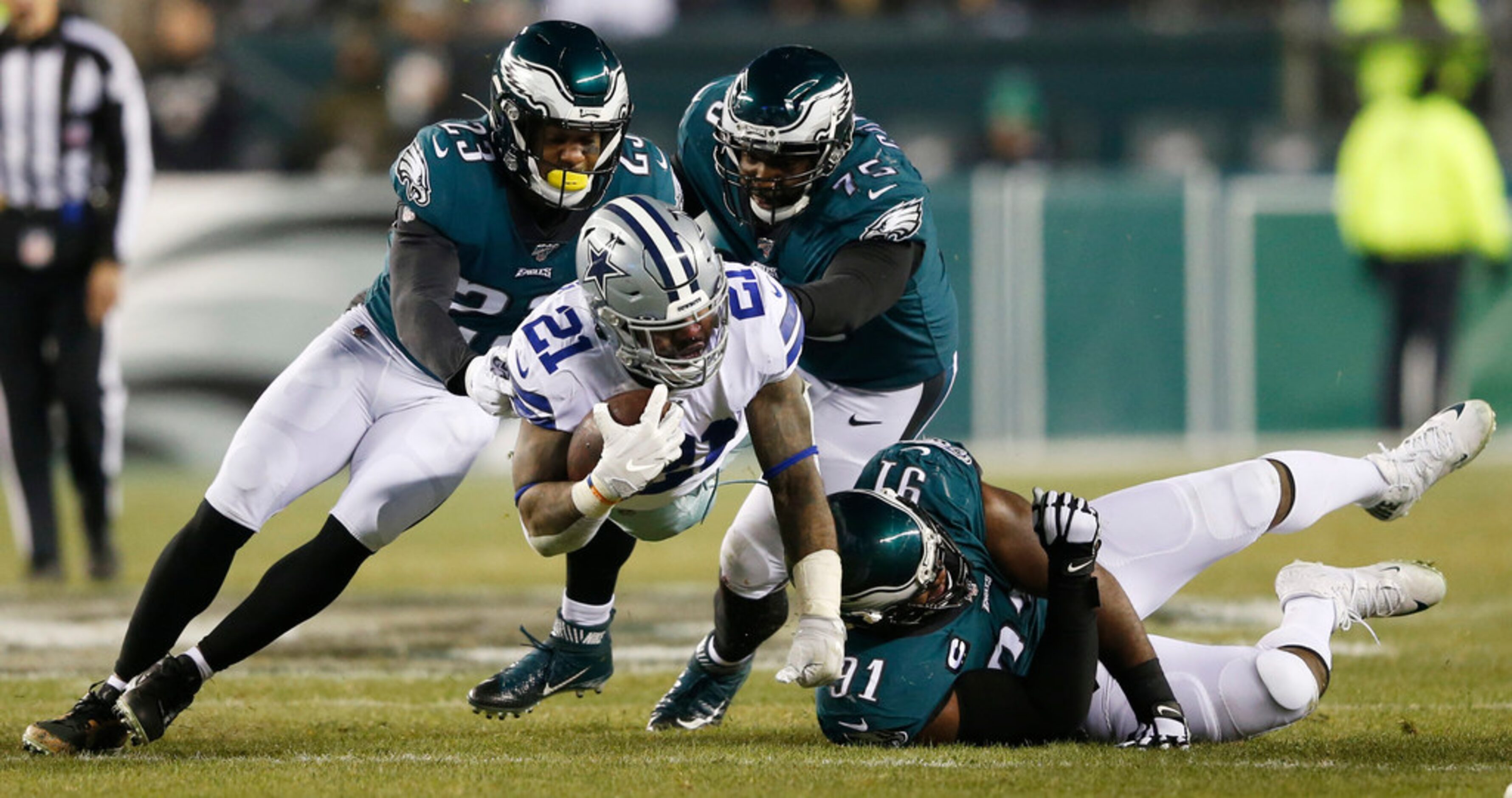 Dallas Cowboys running back Ezekiel Elliott (21) leaps for yards as he is tackled by...