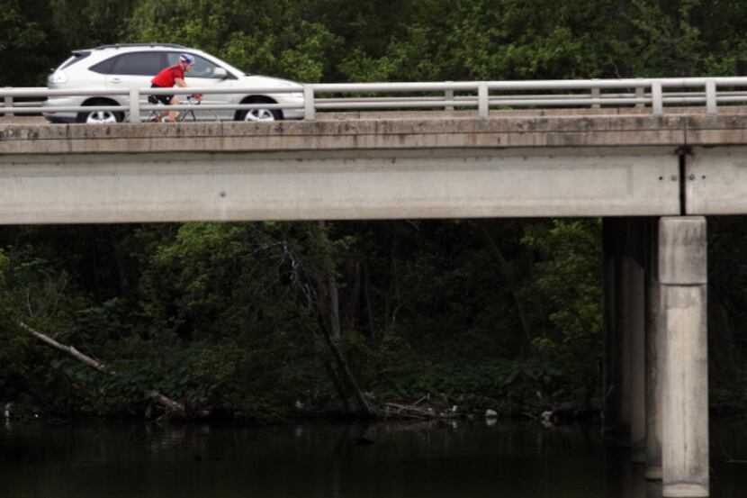 A cyclist shares the road with a car on Mockingbird Lane above White Rock Lake in Dallas.