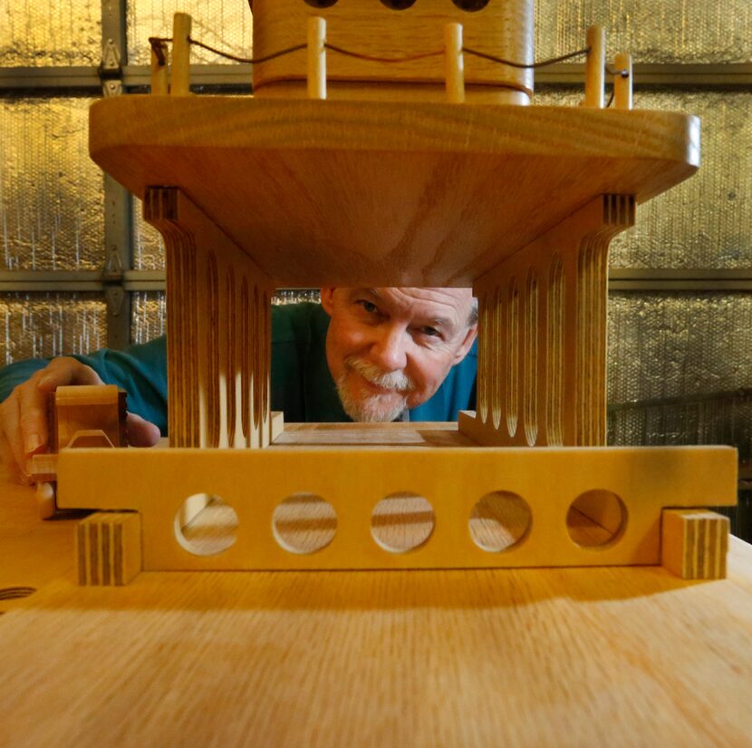 Woodworker and Garland resident John Ellzey is framed by a toy ferry in his shop Tuesday...