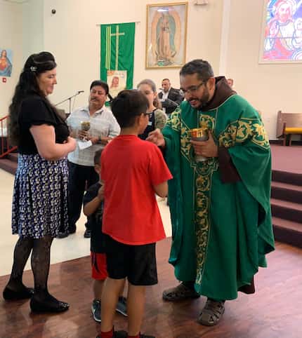 El pastor Sergio Amaya ofrece la comunión durante una misa en la iglesia Santa María...