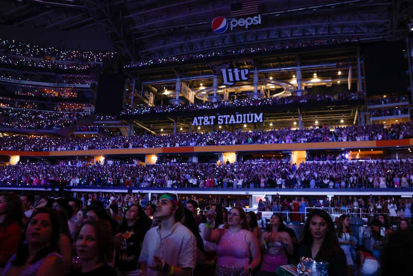 Fans watch and cheer as Taylor Swift performs during the Eras Tour concert at AT&T Stadium...