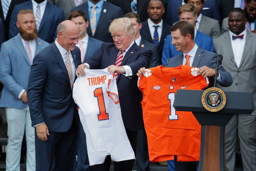 President Donald Trump holds up a jersey given to by Clemson head football coach Dabo...
