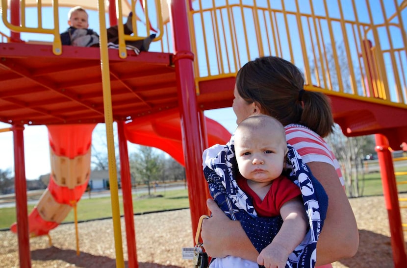 
Cami Evans holds her three-month-old son, Parker, while watching her other son, Hunter, 2,...