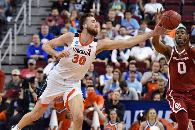 Virginia's Jay Huff stretches out for a loose ball against Oklahoma's Christian James (0)...