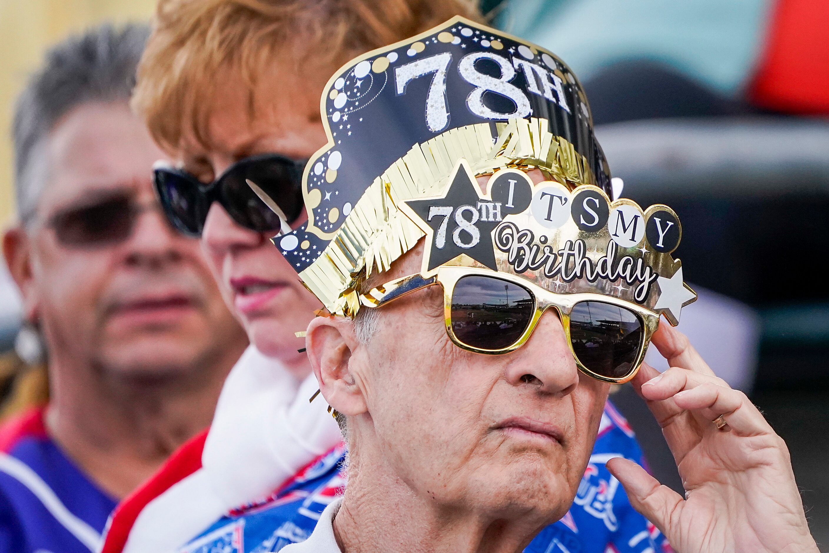 A fan decked out in birthday regalia watches during the seventh inning of a Texas Rangers...