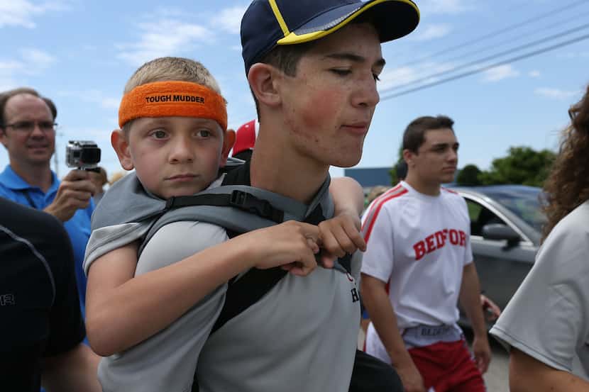 Braden Gandees, 7, rides on his brother Hunter's, 14, shoulders as they close in on the...