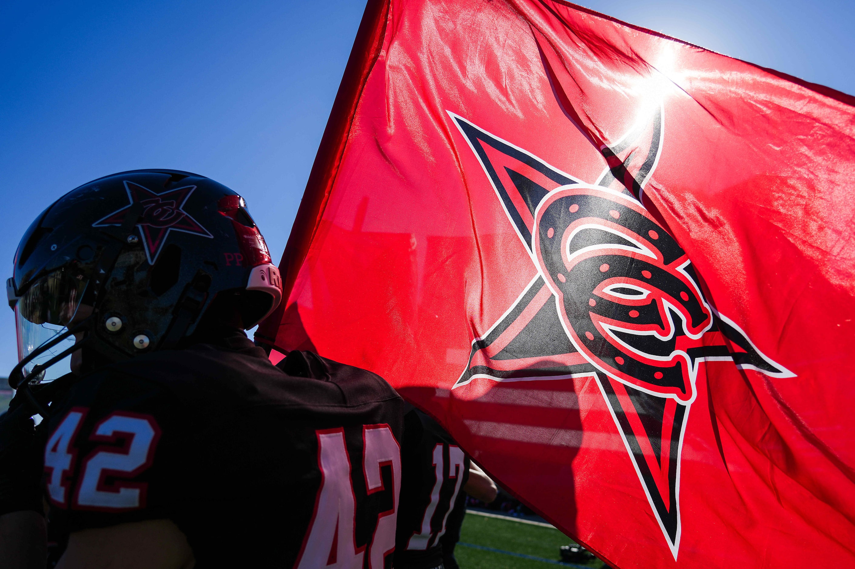 Coppell linebacker Ryker Villines (42) carries a flag as the team takes the field for the...