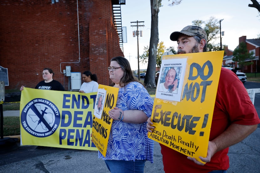 Thomas Roberson, a brother of Robert Roberson and Thomas’s wife Jennifer Roberson hold signs...