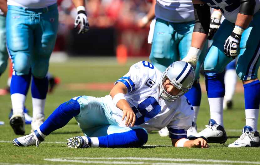 Dallas Cowboys quarterback Tony Romo (9) gets up slow after being knocked to the ground in...