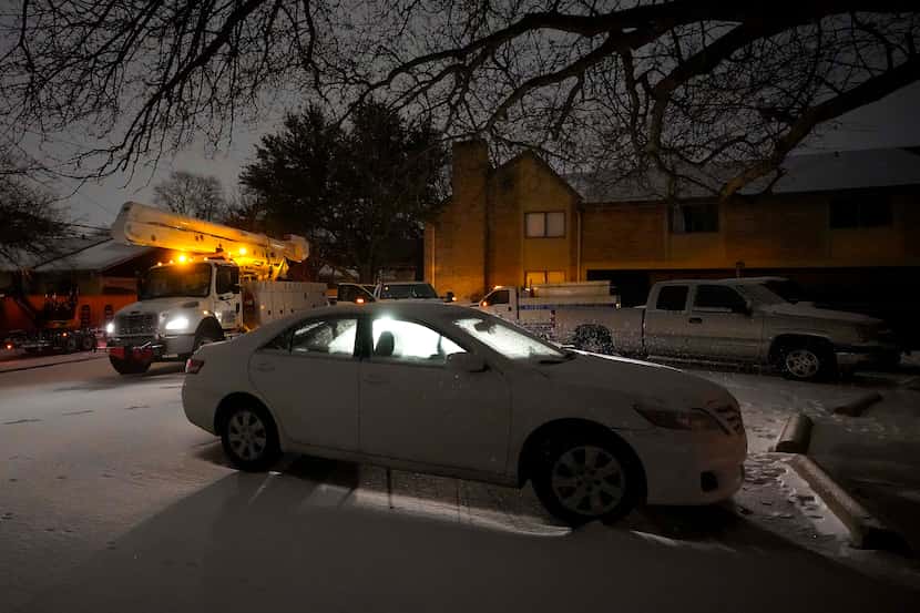 Power crews work in a darkened apartment complex after a second winter storm brought more...