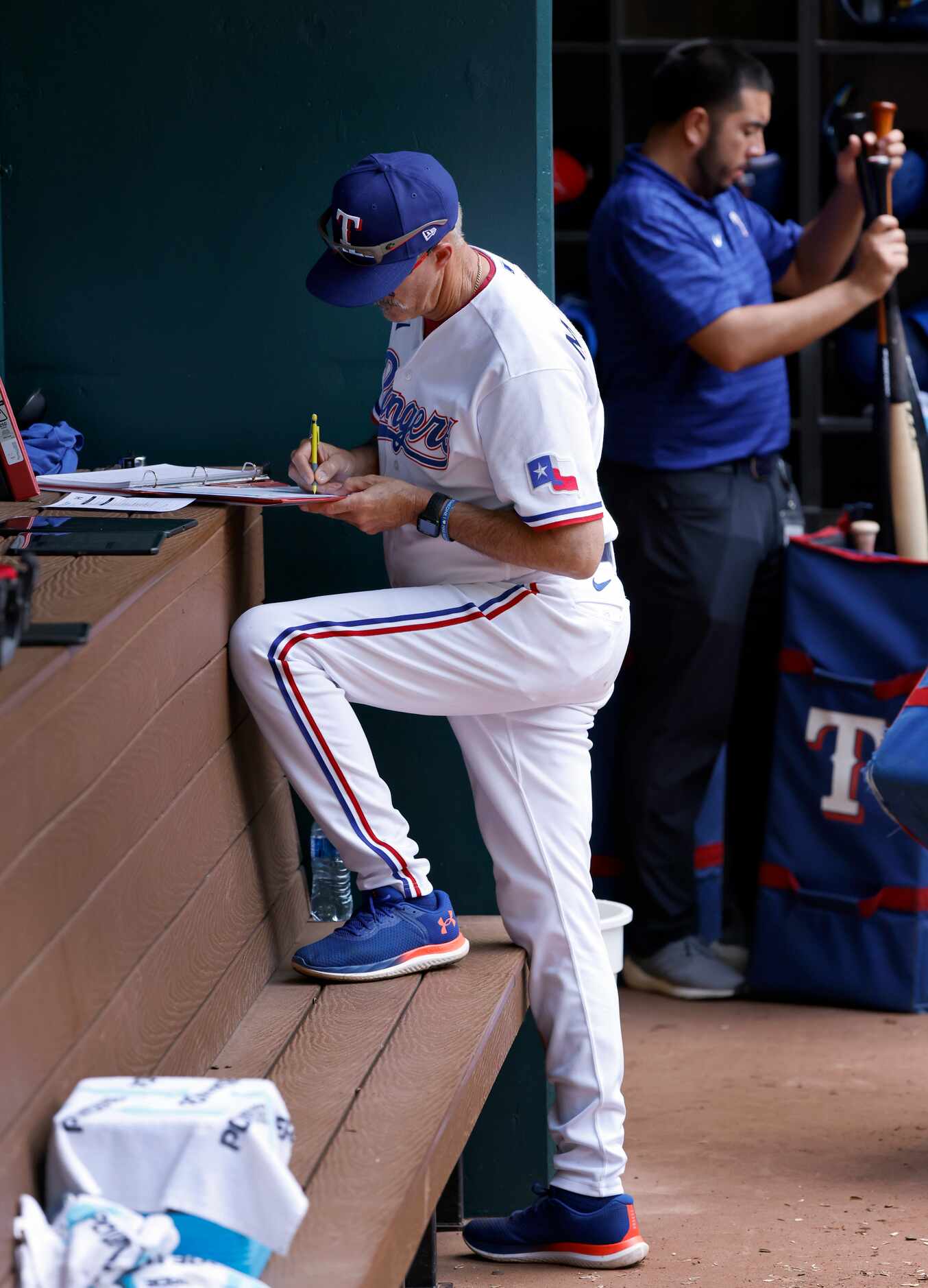 Texas Rangers pitching coach Mike Maddux takes notes in the dugout following their loss to...