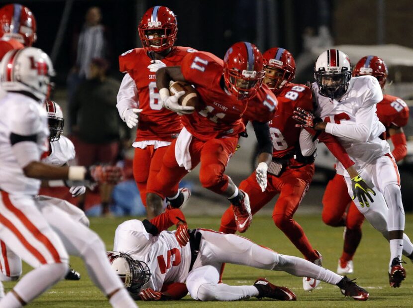 Skyline High's LeDarryl Randolph (11) leaps over Lake Highlands Kimon Malone (5) during a...