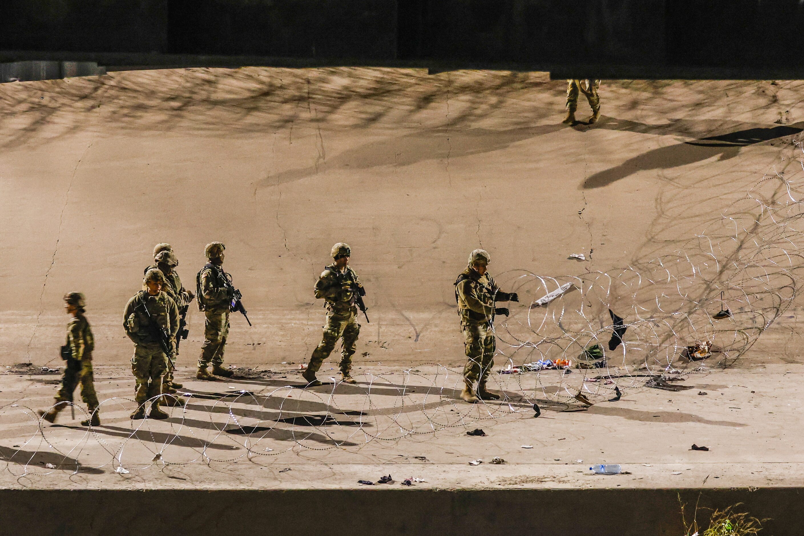 Texas National Guardmen work on extending the barricade on the U.S. side of the border in El...