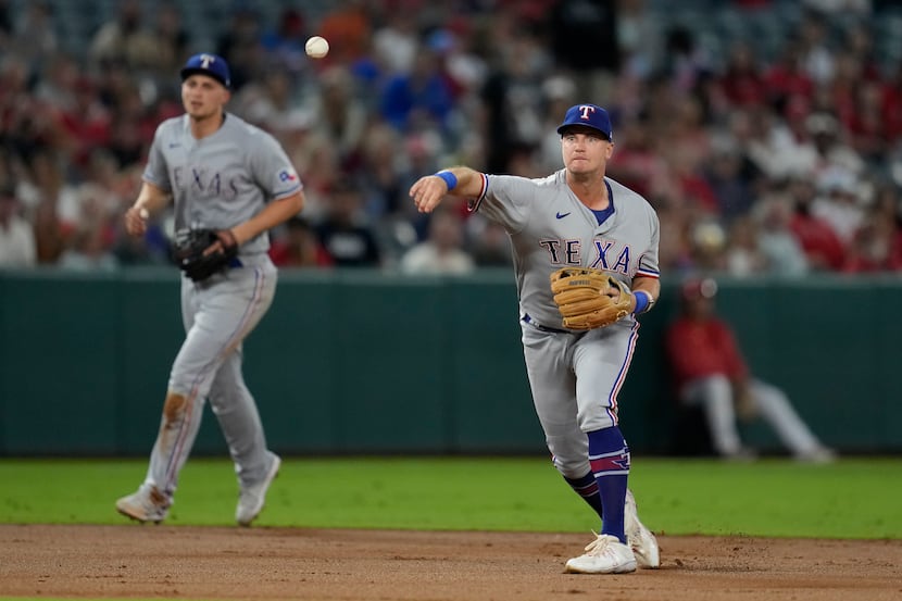 Texas Rangers third baseman Josh Jung, right, throws to first to out Los Angeles Angels...