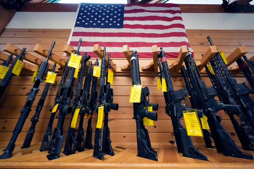 A variety of AR-15-style rifles are displayed under an American flag at the Kittery Trading...