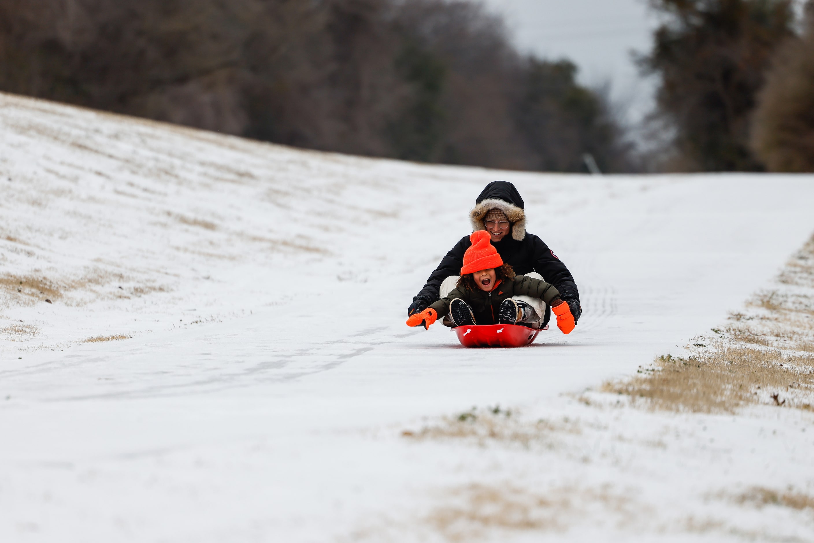 Lauren Jarret, 34, with Miles Jarret, 4, slide down the hillside covered by sleet near at...