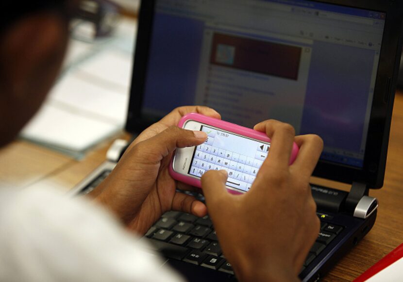 Nisha Issac, 15, of Carrollton, uses her phone to text an answer during her world geography...