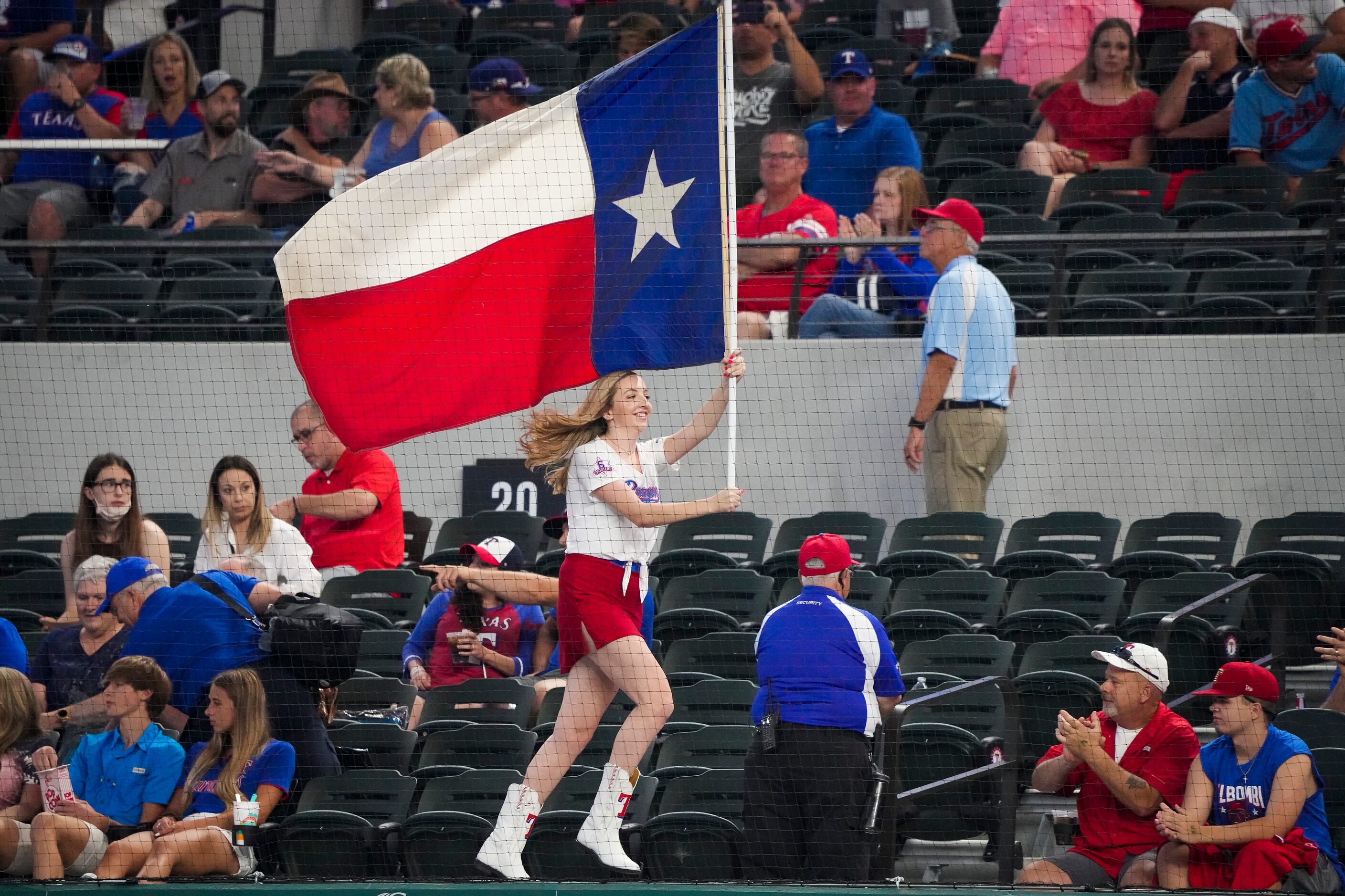 A member of the Texas Rangers Six Shooters squad runs a flag across the dugout before a game...