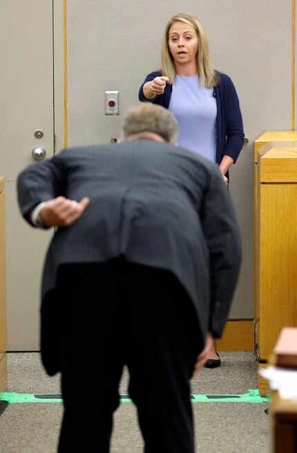 Prosecutor Jason Hermus (back to camera) asks Amber Guyger to pretend to aim a gun at him...
