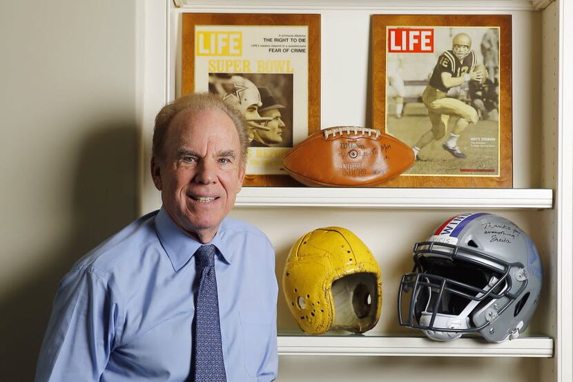 Hall of Fame Dallas Cowboys quarterback Roger Staubach poses with the football helmets that...