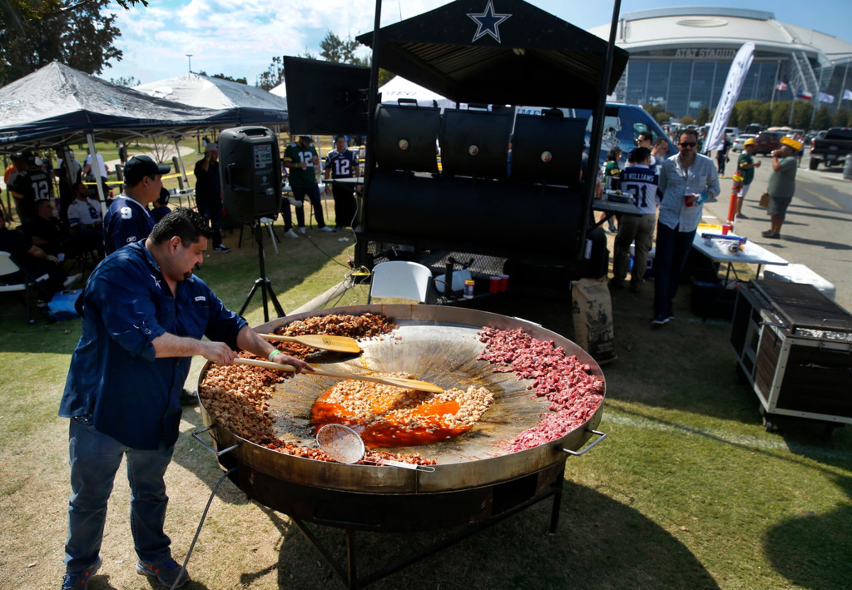 Dallas Cowboys fan Oscar Cantu of McAllen, Texas uses a canoe oar to stir discada, a mixed...