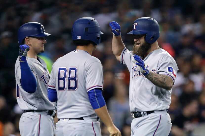 Texas Rangers' Mike Napoli, right, is greeted at home plate after his solo home run during...