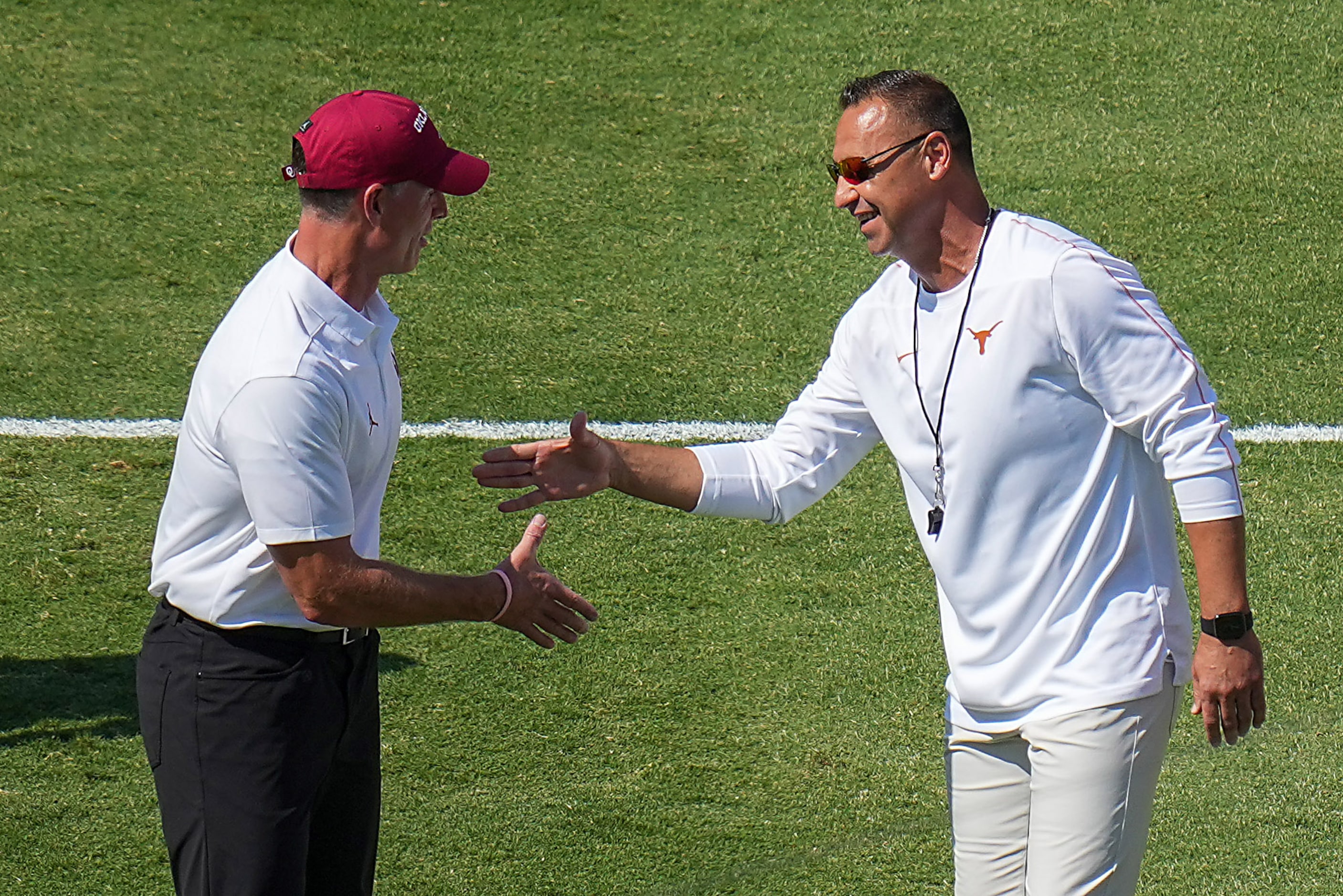 Oklahoma head coach Brent Venables (left) shakes hands with Texas head coach Steve Sarkisian...