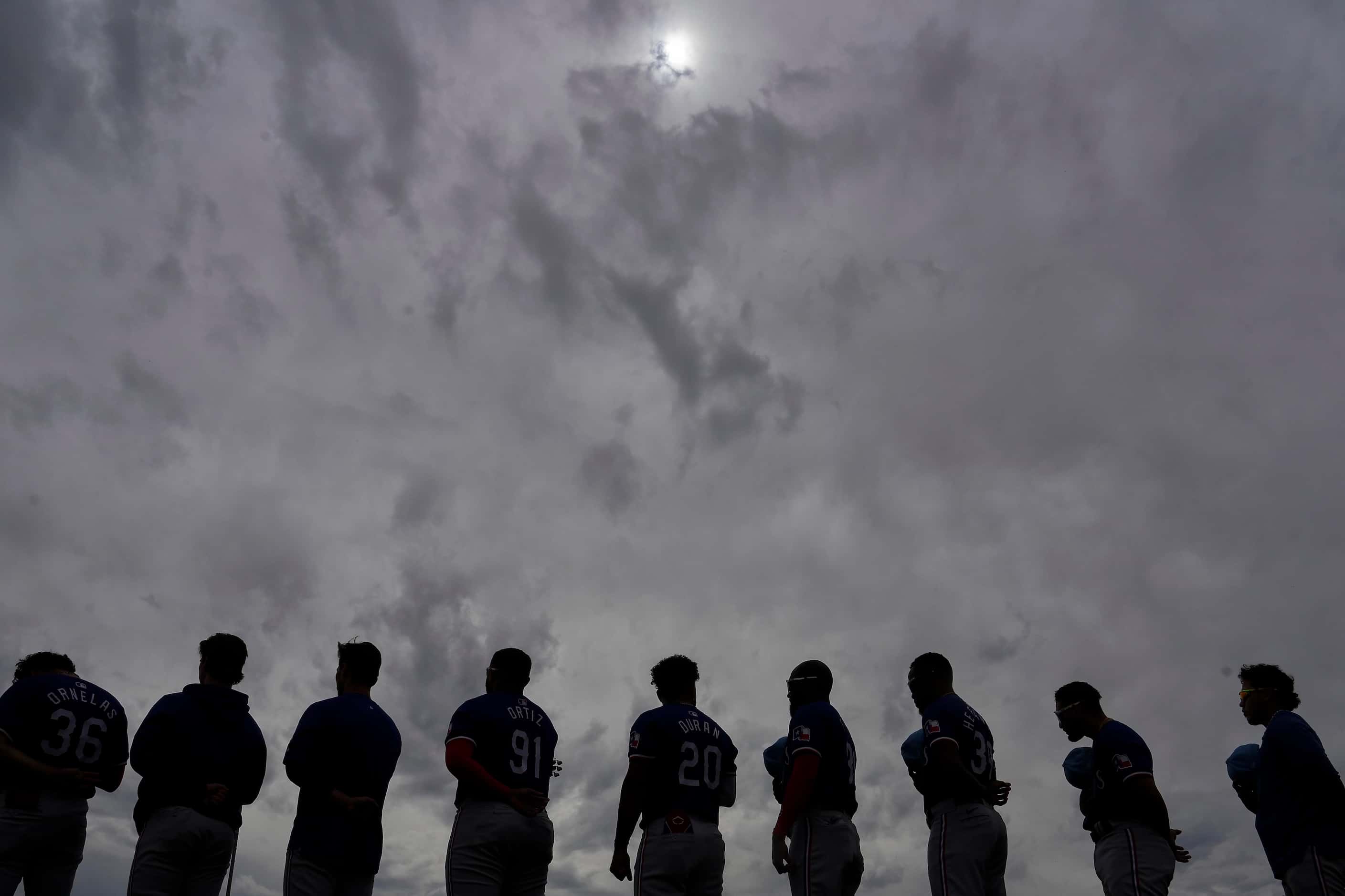 Texas Rangers players stand for the national anthem before a spring training game against...