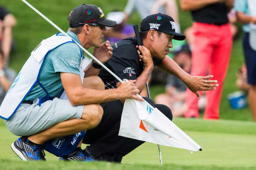 James Hahn and his caddie Mark Urbanek line up a putt at the 12th green during round four of...