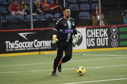 A Dallas Sidekicks player runs down a soccer field and kicks a soccer ball.