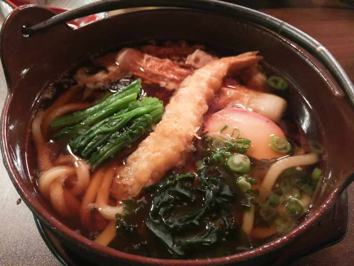 Nabeyaki udon is garnished with greens, shrimp tempura, fish cake and more. 