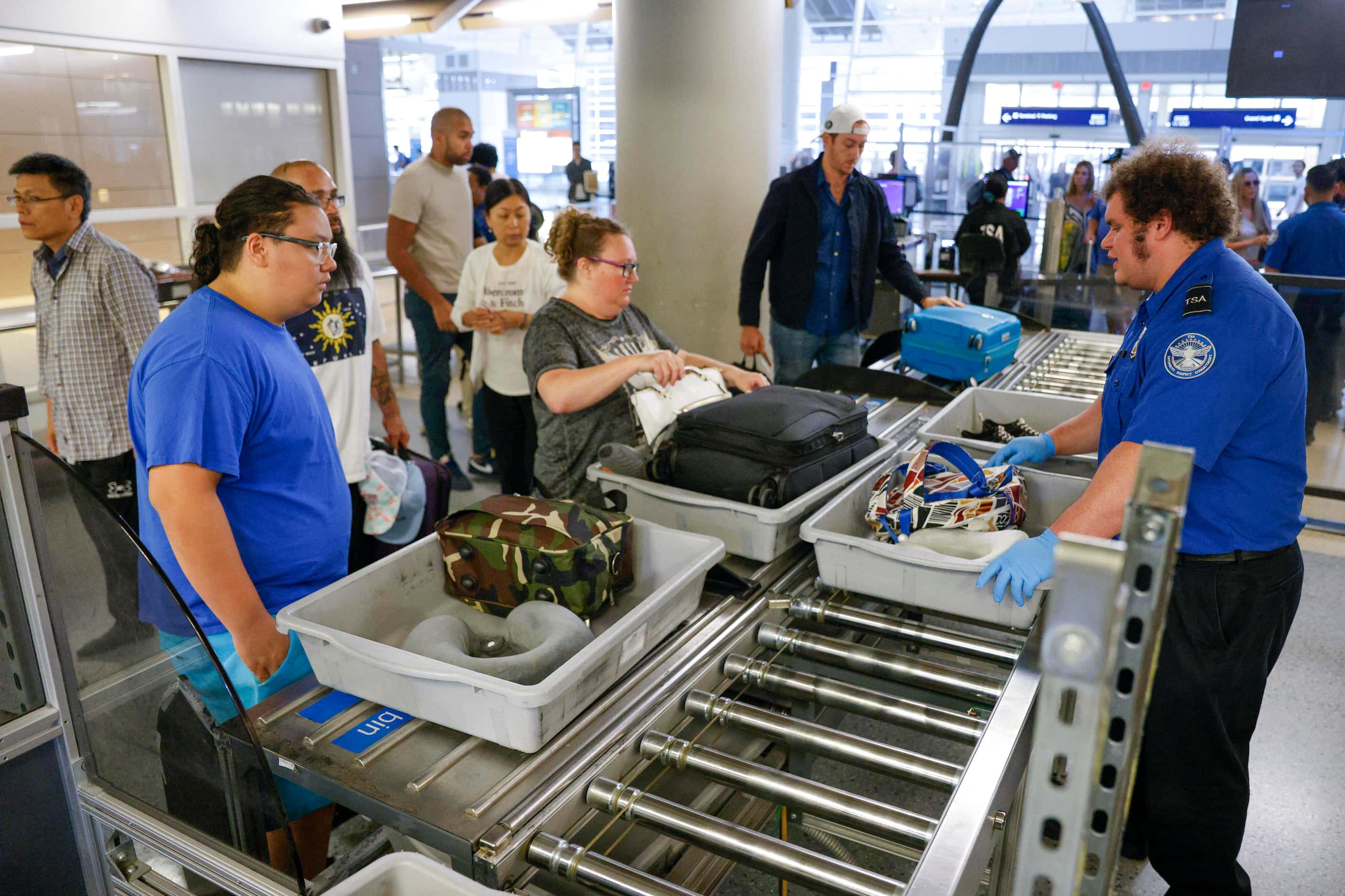 TSA transportation security officer Andrew Ott helps travelers load their belongings into...