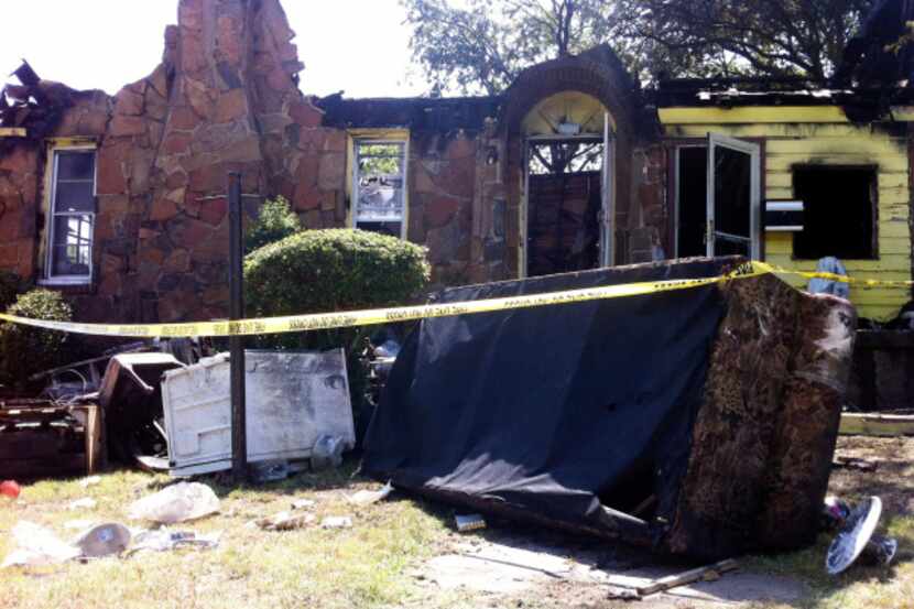 Furniture is strewn in front of the charred rubble of a home on Berwick Avenue. Dallas...
