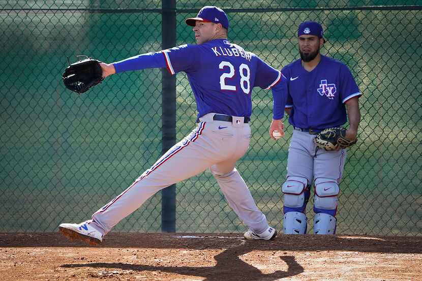 Texas Rangers pitcher Corey Kluber throws in the bullpen as catcher Robinson Chirinos looks...