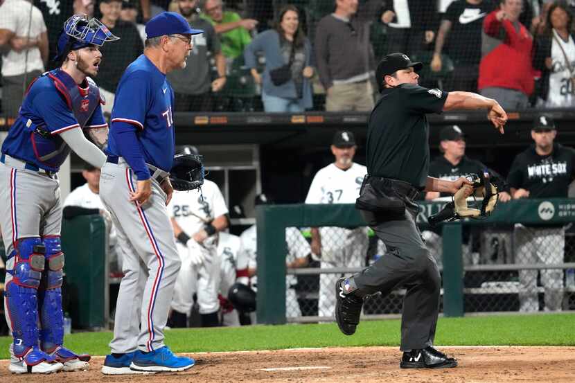 Texas Rangers catcher Jonah Heim, left, reacts after manager Bruce Bochy, center, was...