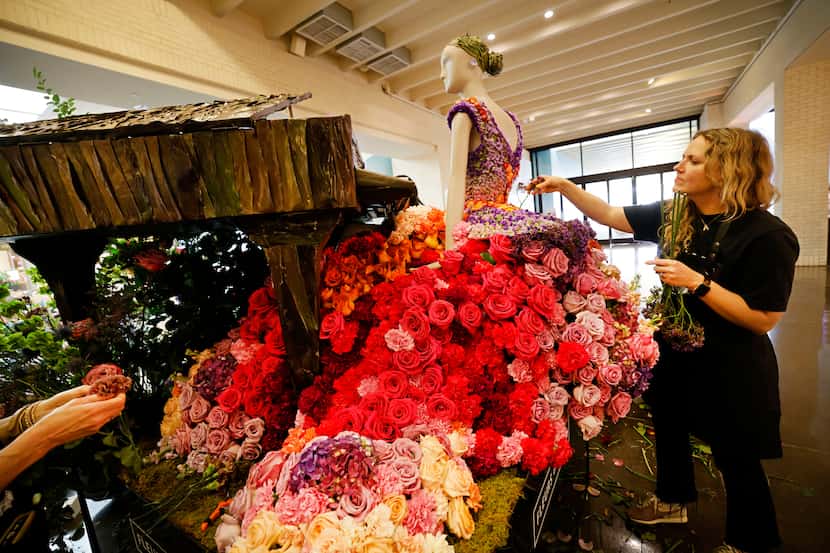 Kate McLeod, owner of Kate McLeod Studio, creates a flower dress for a mannequin with her...