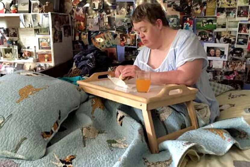 Alexandra “Xan” Marcellus, who was born with Down syndrome, eats breakfast in bed. Her large...