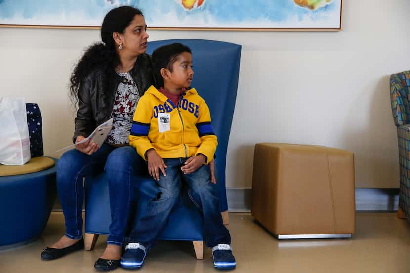 Akshaj Nagilla, 8, of Frisco, sits in a waiting room with his mother Anitha Nagilla, as they...