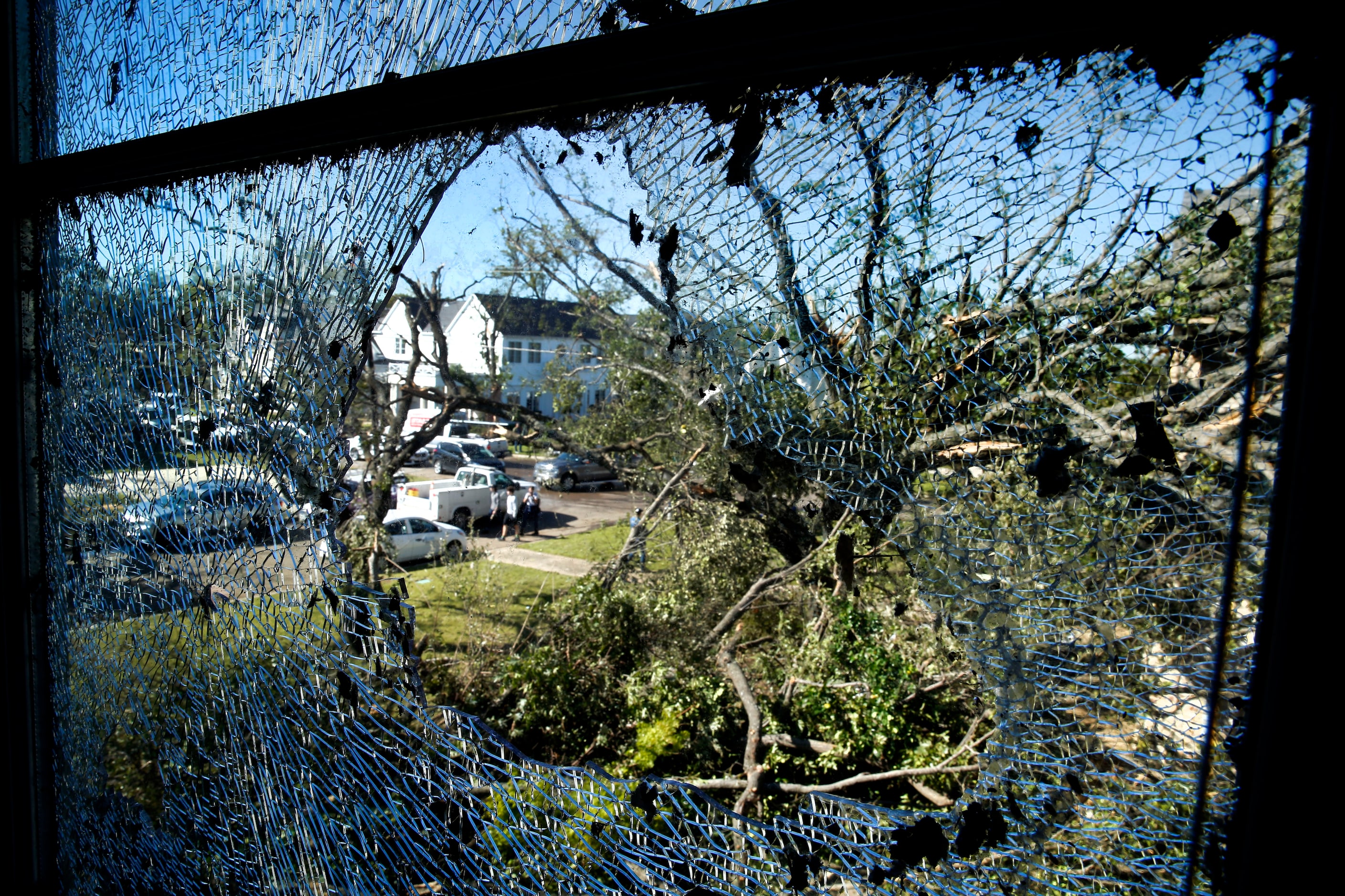 Damaged homes and down trees on Pemberton Drive in Dallas are seen through Eva wiley's...