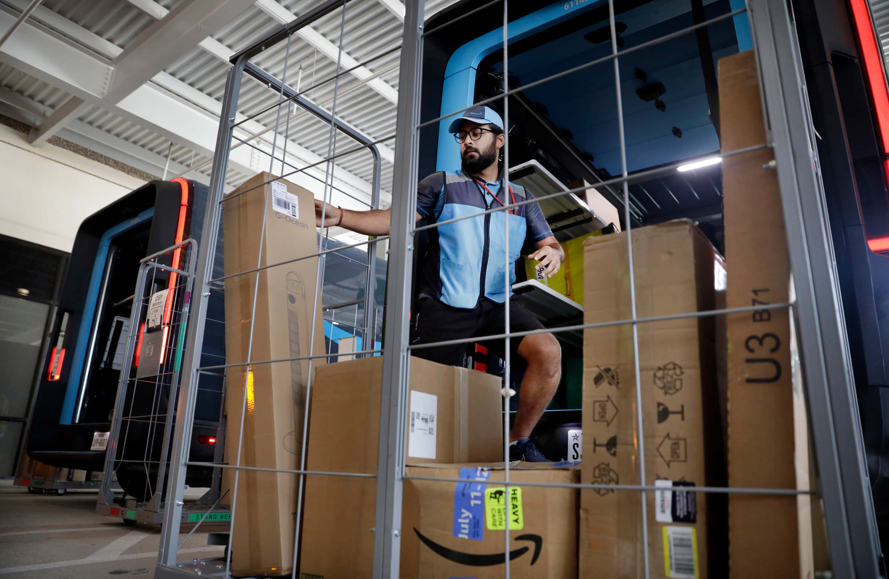 Delivery associate Ali Haider loads packages into his Electronic Delivery Vehicle (EDV) at...