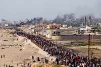 Palestinians are waiting for aid trucks to cross in central Gaza Strip on Sunday, May 19,...