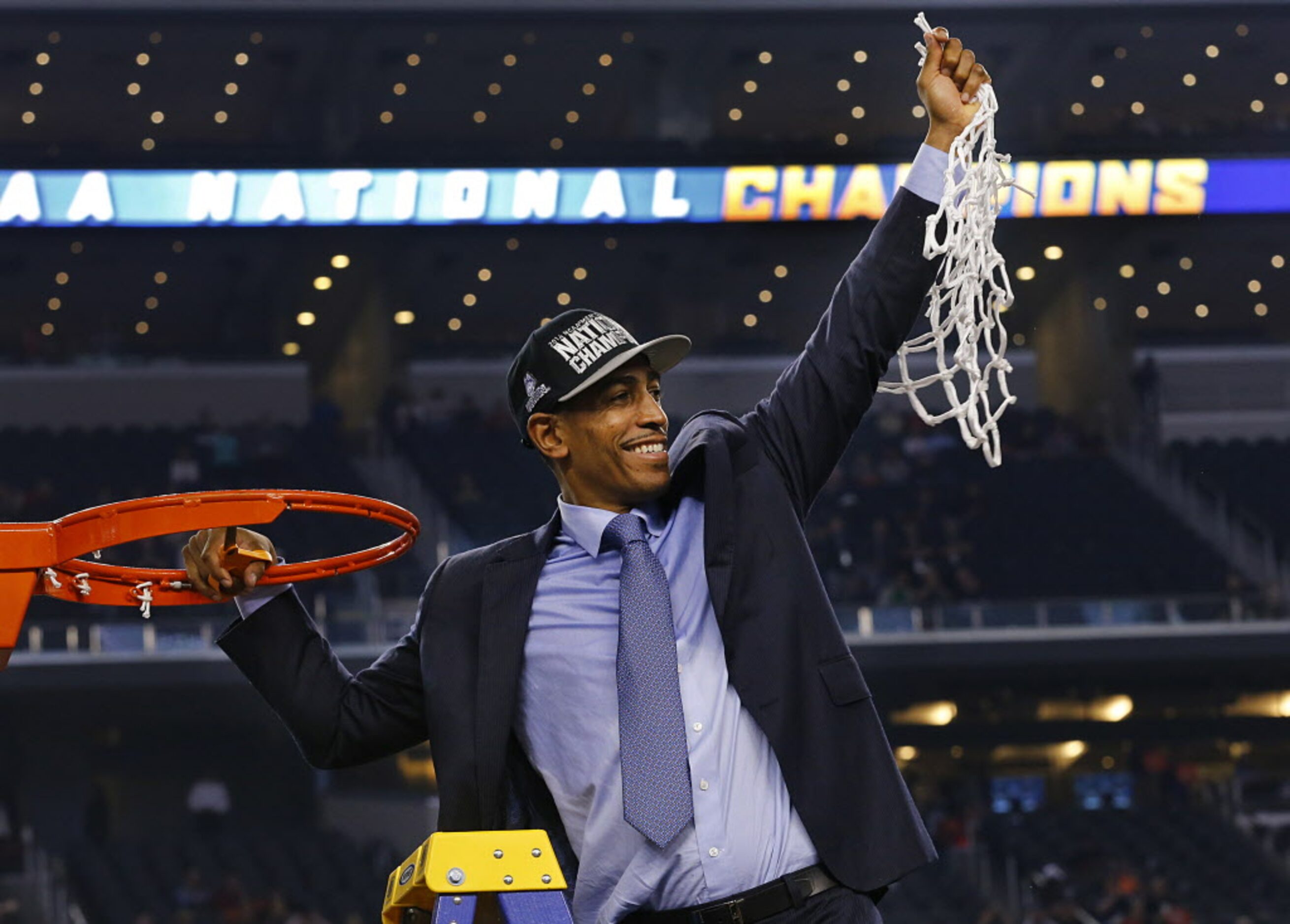 Connecticut Huskies head coach Kevin Ollie swings the net after cutting it off the hoop...