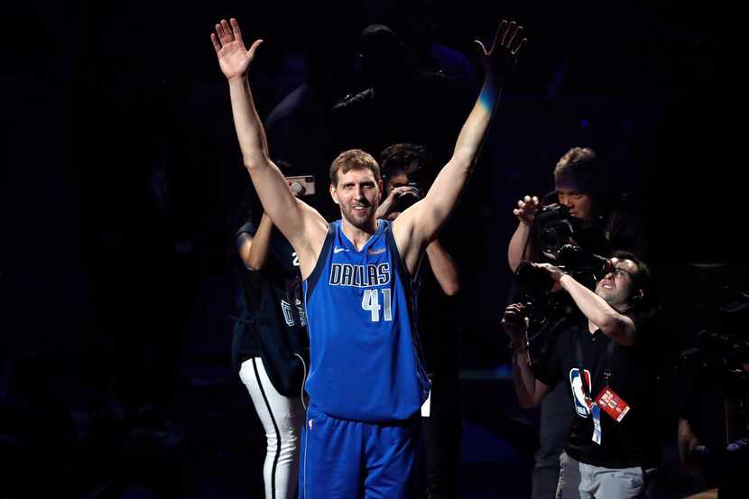 Dallas Mavericks' Dirk Nowitzki acknowledges cheers from fans as he walks off the court...