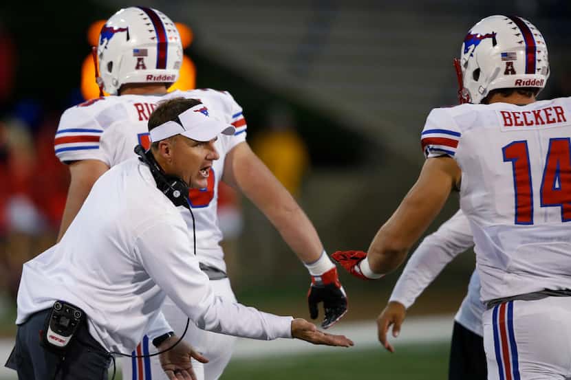SMU head coach Chad Morris, left, greets his players as they come back to the bench...