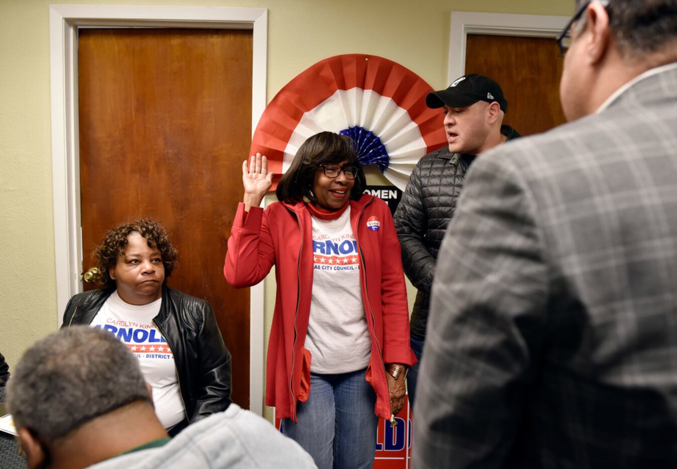 Carolyn King Arnold, center, raises her right hand as if she was being sworn in as she...