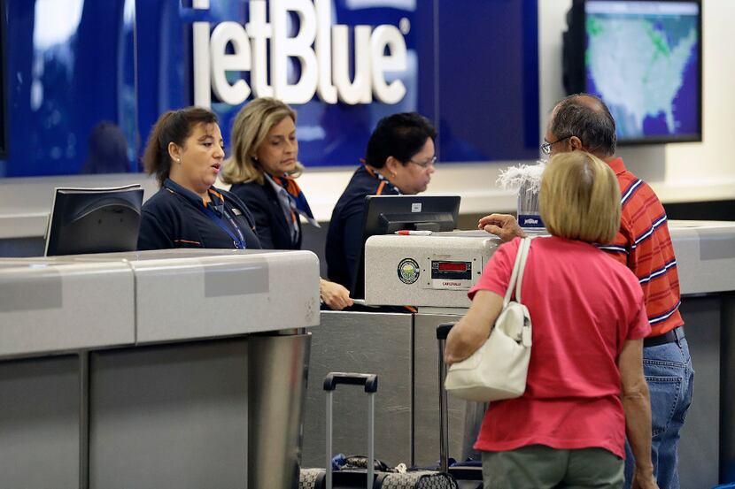 In this Wednesday, Oct. 26, 2016, photo, JetBlue Airways ticket agents assist passengers at...