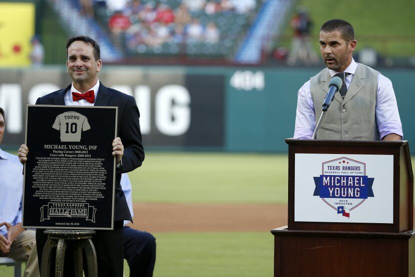 Michael Young (right) speaks after being inducted as a new member of the Rangers Baseball...